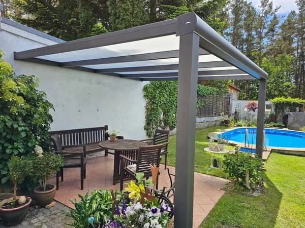 Offenes Dach über einem Sitzplatz im Garten, mit Tisch, Stühlen und einem Pool daneben.