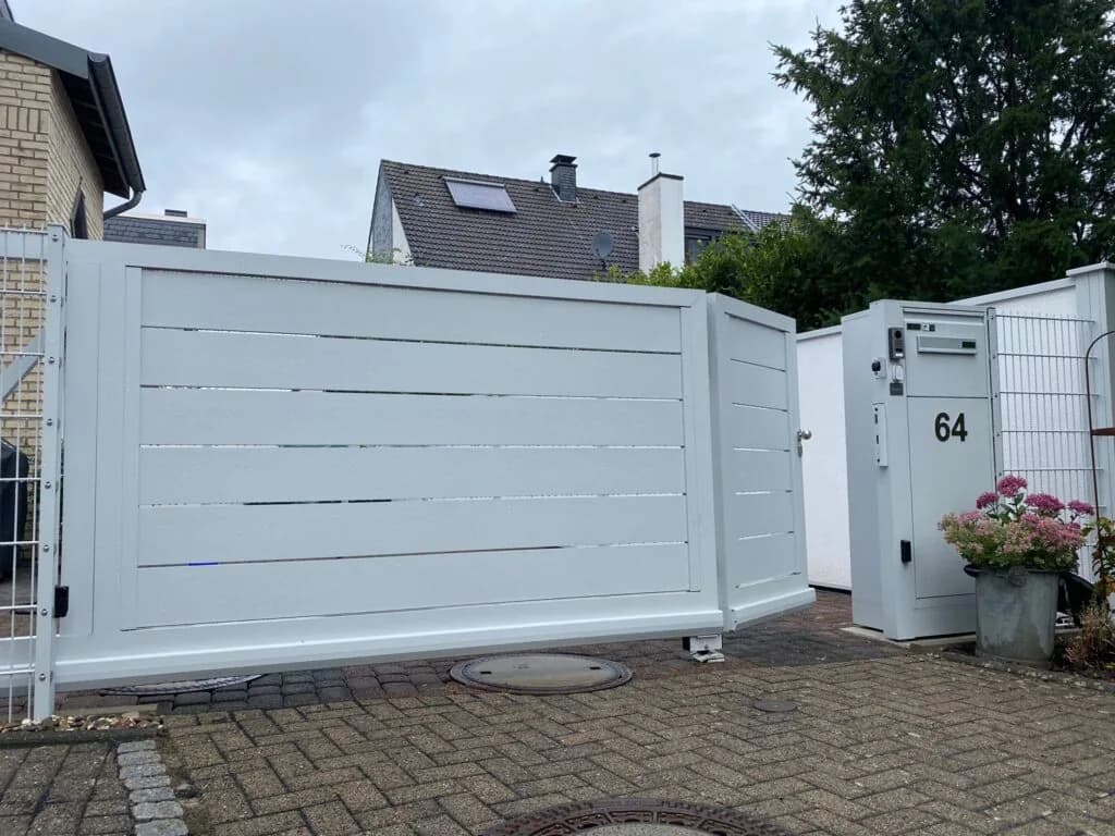 Weißes Tor mit waagerechten Füllungen und schmalem Durchgang neben einem Hauseingang.